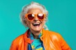 © iridescentstreet - Happy senior woman in colorful neon outfit, funny sunglasses and extravagant style, laughing and smiling, trendy grandma posing in studio