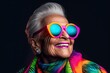 © iridescentstreet - Happy senior woman in colorful neon outfit, funny sunglasses and extravagant style, laughing and smiling, trendy grandma posing in studio