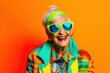 Happy senior woman in colorful neon outfit, funny sunglasses and extravagant style, laughing and smiling, trendy grandma posing in studio