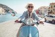 Leinwandbild Motiv Cheerful senior woman riding blue scooter in Italy, retired granny enjoying summer vacation, trendy bike road trip