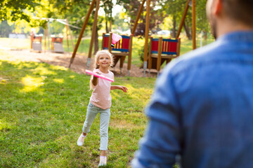 Happy cute girl playing badminton with her father in the park, spending active free time together outdoors