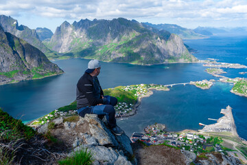 Relaxed happy hiker enjoys stunning views on Reinebringen peaks of Lofoten islands, fjords, Norway. Traveling Man enjoying Norway mountains view Travel Lifestyle concept adventure active