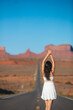 © travnikovstudio - Happy young woman on the famous road to Monument Valley in Utah on her trip in famous Canyon in USA. Amazing view of the Monument valley.