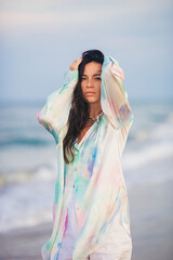 Young happy woman on the beach enjoy her summer vacation. Woman walking along the sea in evening. 