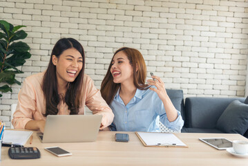 Wall Mural - Two asian Female freelance reading financial graph charts Planning analyzing marketing data. Asian people team working office firm. Two businesswomen team meeting using laptop at company office desk.