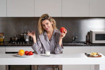 Apple and milk for breakfast. Woman eat apple and drink milk for healthy food in the kitchen. Healthy lifestyle.