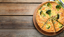 Piece of delicious homemade quiche with salmon and broccoli on wooden table, top view. Space for text