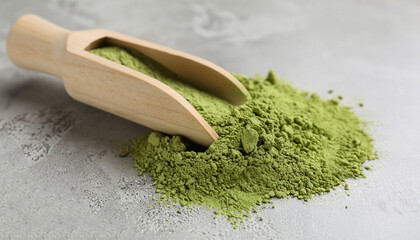 Wall Mural - Green matcha powder and bamboo scoop on light grey table, closeup