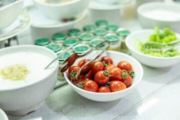 Canvas Print - Cocktail tomatoes in a bowl on the buffet table, next to yogurt and lettuce.