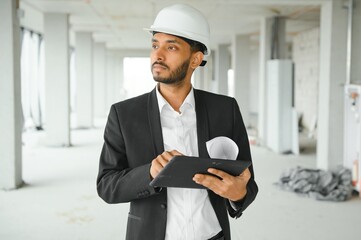 Asian engineer handsome man or architect with white safety helmet in construction site. Standing at modern building construction. Worker asian man working project building