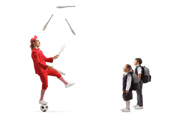 Wall Mural - Children watching a man in a red suit standing on a ball and juggling