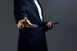 © Pheniti - Businessman using a phone and pointing a finger against dark background.