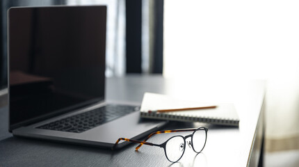 Wall Mural - laptop, glasses and notebok on the desktop on a blurred background.