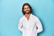 © Asier - Bearded man in a white shirt, blue backdrop happy, smiling and cheerful.