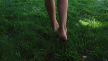 Legs Of Girl Child Teenager Barefoot Walking Away From Camera Step On Green Grass Or Lawn Rear View