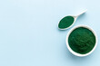 Spirulina or seaweed powder in bowl and in spoon, top view. Super food concept