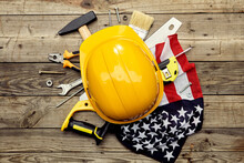 Yellow Safety Helmet, American Flag And Construction Tools On Wooden Table. Happy Labor Day Concept.