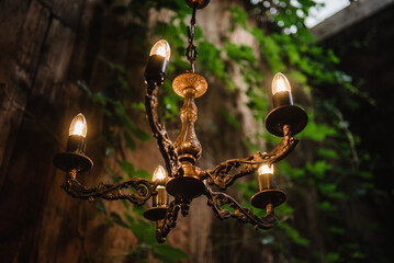 Chandelier with LED lamps in a modern house in nature style. Vintage pendants. Decorating a wedding dinner with antique chandeliers. Hanging lamp in luxury retro style on dark background Closeup.