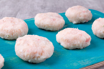 Cooking cutlets with codfish and shrimps. Uncooked patties on turquoise board