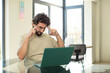 young adult bearded man with a laptop feeling confused or doubting, concentrating on an idea, looking to copy space on side