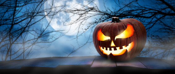 Wall Mural - the spooky haunted evil glowing eyes of jack o' lanterns, halloween pumpkin, on the right of a woode