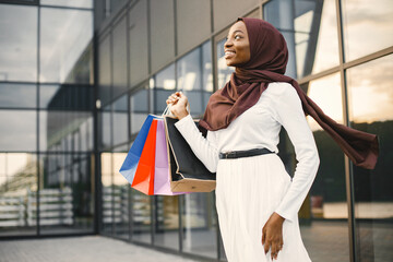 Wall Mural - Arabic woman wearing hijab standing with shopping bags near mall