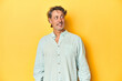 © Asier - Middle-aged man posing on a yellow backdrop relaxed and happy laughing, neck stretched showing teeth.