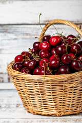 Wall Mural - Fresh cherry in a wicker basket over wooden background. Cherry harvest season concept. Healthy and fresh fruit. Close up