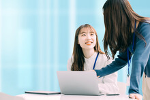オフィスでパソコンを使ってミーティングをする2人の若い日本人ビジネスウーマン