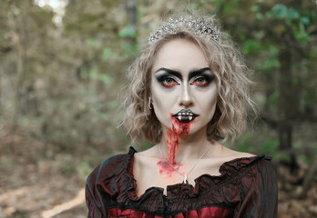 A woman in the form of a vampire or witch with white makeup on her face. woman looking at camera