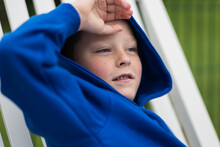 Adorable Happy Kid In Blue Hoodie Sitting In Daylight