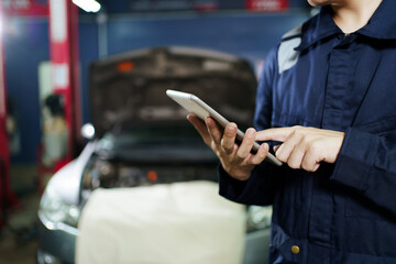 Professional Asian vehicle technician posing for photography in garage. Handsome Asian repairman or technician examining a vehicle in garage.