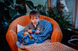 © Иванна Емельянова - Little toddler boy having rest covered himself in blue pleid in straw chair