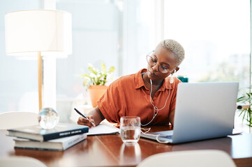 Poster - Dream big and do bigger. Shot of a young businesswoman wearing earphones while writing notes in an office.