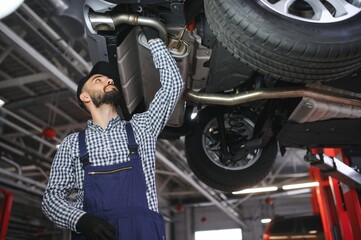 Wall Mural - Adult man in blue colored uniform works in the automobile salon.