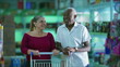 © Marco - Happy diverse customers smiling inside grocery business store with shopping cart