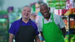 © Marco - Happy diverse senior workers standing at grocery store smiling at camera wearing uniforms. Older Brazilian staff workers