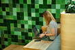 © Lazy_Bear - Woman using laptop in coworking with green plants. Female freelancer typing on laptop keyboard. Online work in cafe