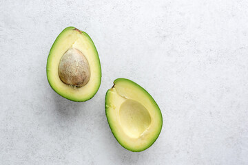 Avocado halves on grey background, healthy vegan food, top view copy space