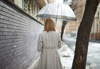 Sticker - Not every day can be sunny. Rearview shot of a woman walking down a street in the rain and holding an umbrella.