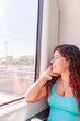 © Sangiao_Photography - Train traveler. Hispanic mid-adult woman looking through the window on holiday lifestyle vacation