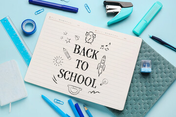 Notebook with text BACK TO SCHOOL and different stationery on light blue background