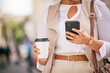 © Bettencourt/peopleimages.com - Phone, coffee and hands of person walking and travel in city typing on social media, online or internet. Connection, gps and employee texting a contact via email, web or mobile app in the morning