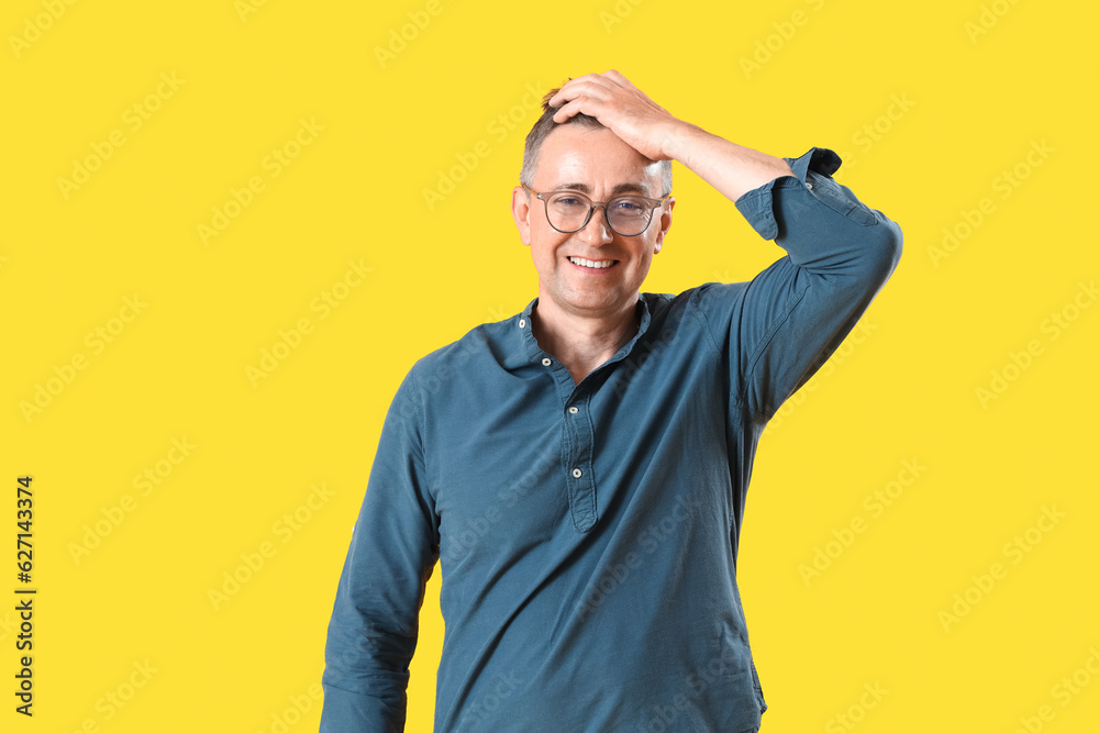 Mature man in eyeglasses on yellow background
