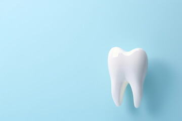 model of a healthy white tooth on a blue background with copy space, dental clinic ad