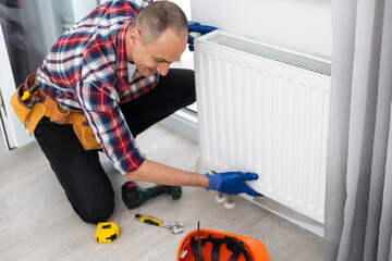 Repair heating radiator close-up. man repairing radiator with wrench. Removing air from the radiator.