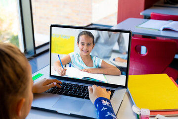 Poster - Rear view of caucasian girl using laptop while having a video call with a biracial girl at school