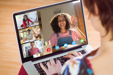 Poster - Rear view of a caucasian girl having a video conference with diverse students on laptop at home