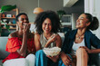 © oneinchpunch - Beautiful and young latin american women having fun and bonding at home eating popcorn on sofa - Three pretty hispanic adult female spending time together watching television