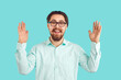 © Studio Romantic - Happy joyful young man in shirt and glasses holding hands apart to show how huge something is. Funny cheerful excited nerd student on blue background telling and boasting about object of very big size